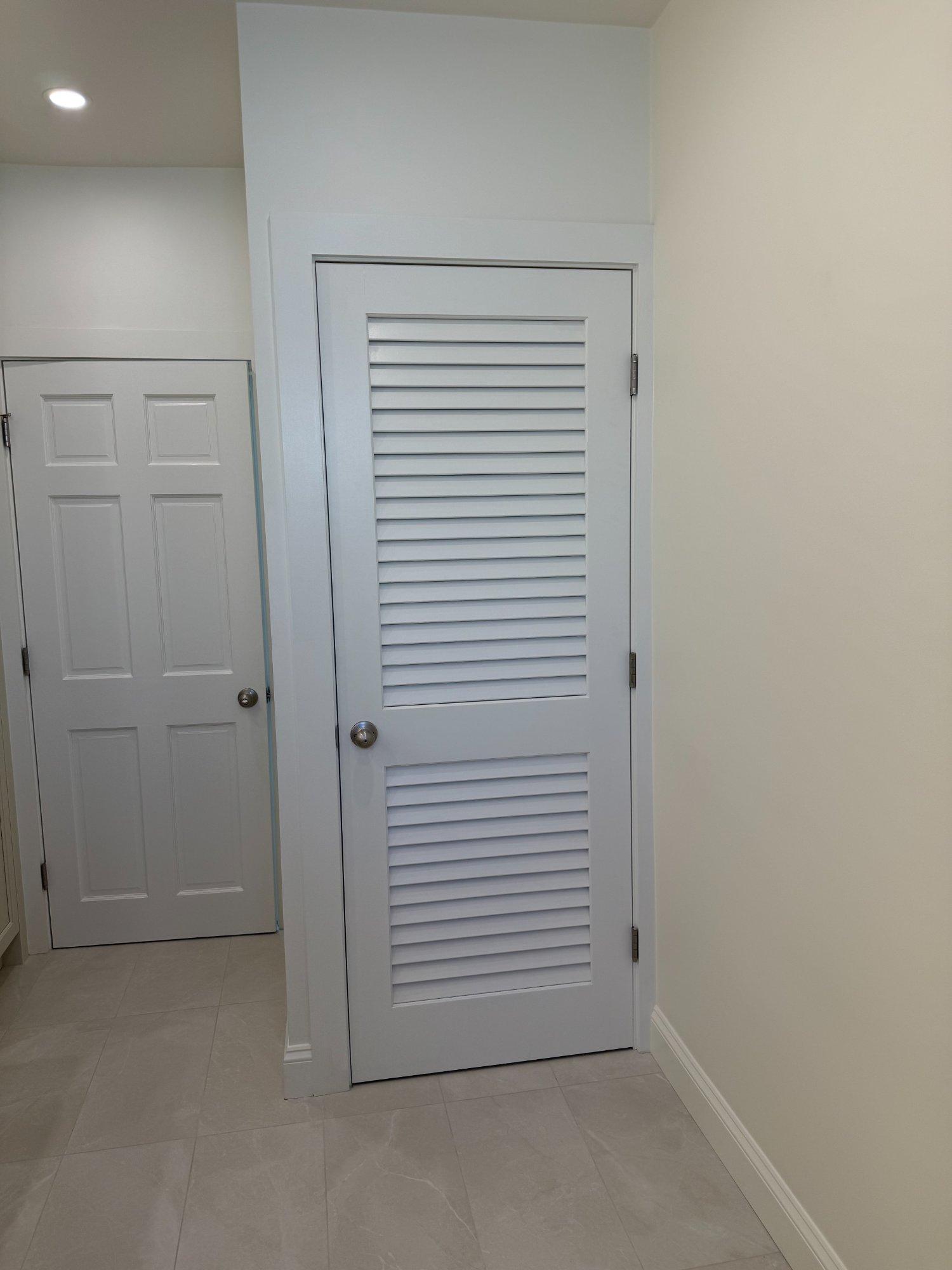 Dedicated laundry room with louvered door and large-format porcelain tile floor