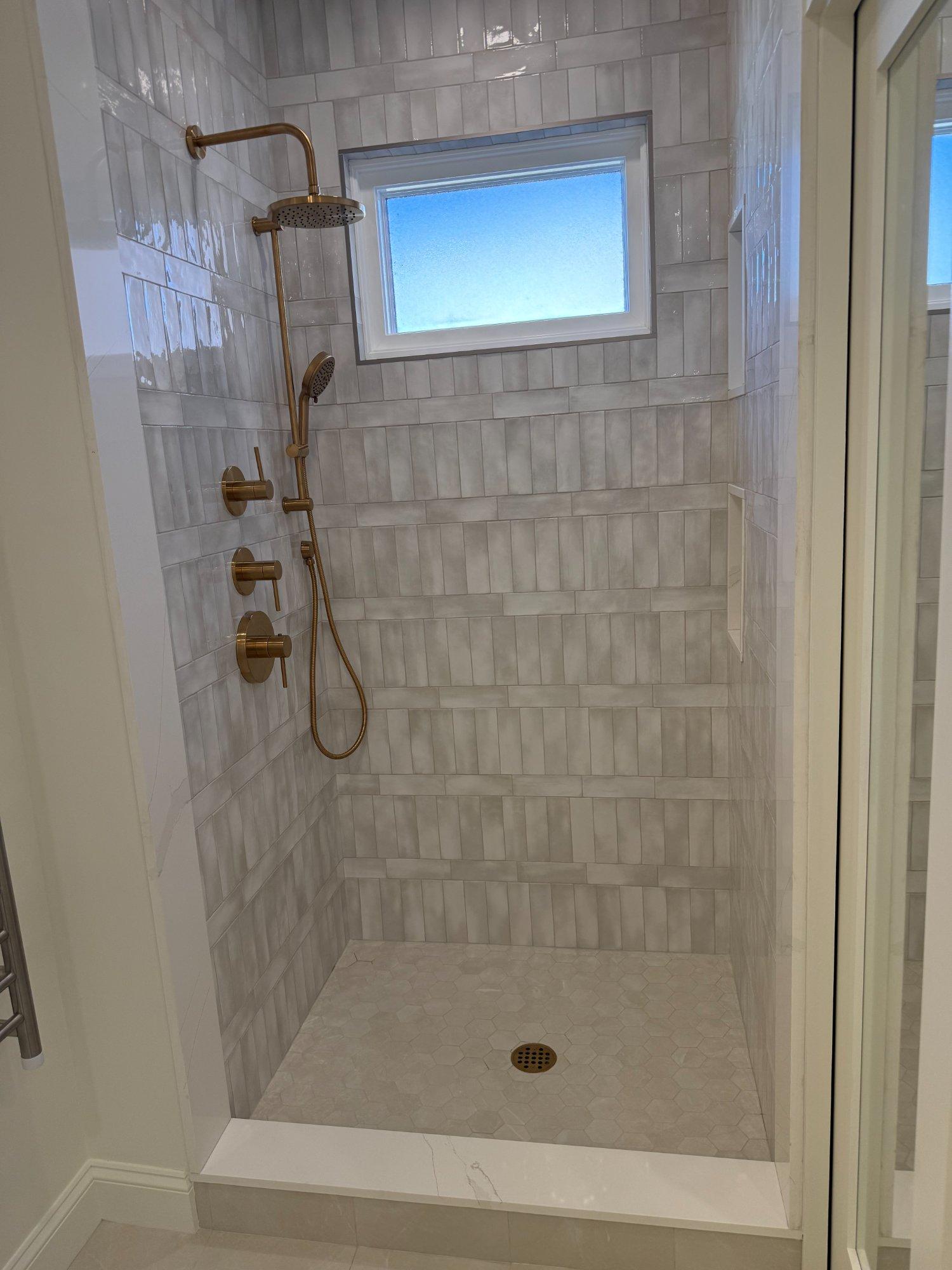 Walk-in shower with handmade tile walls, built-in bench and brushed gold rain head