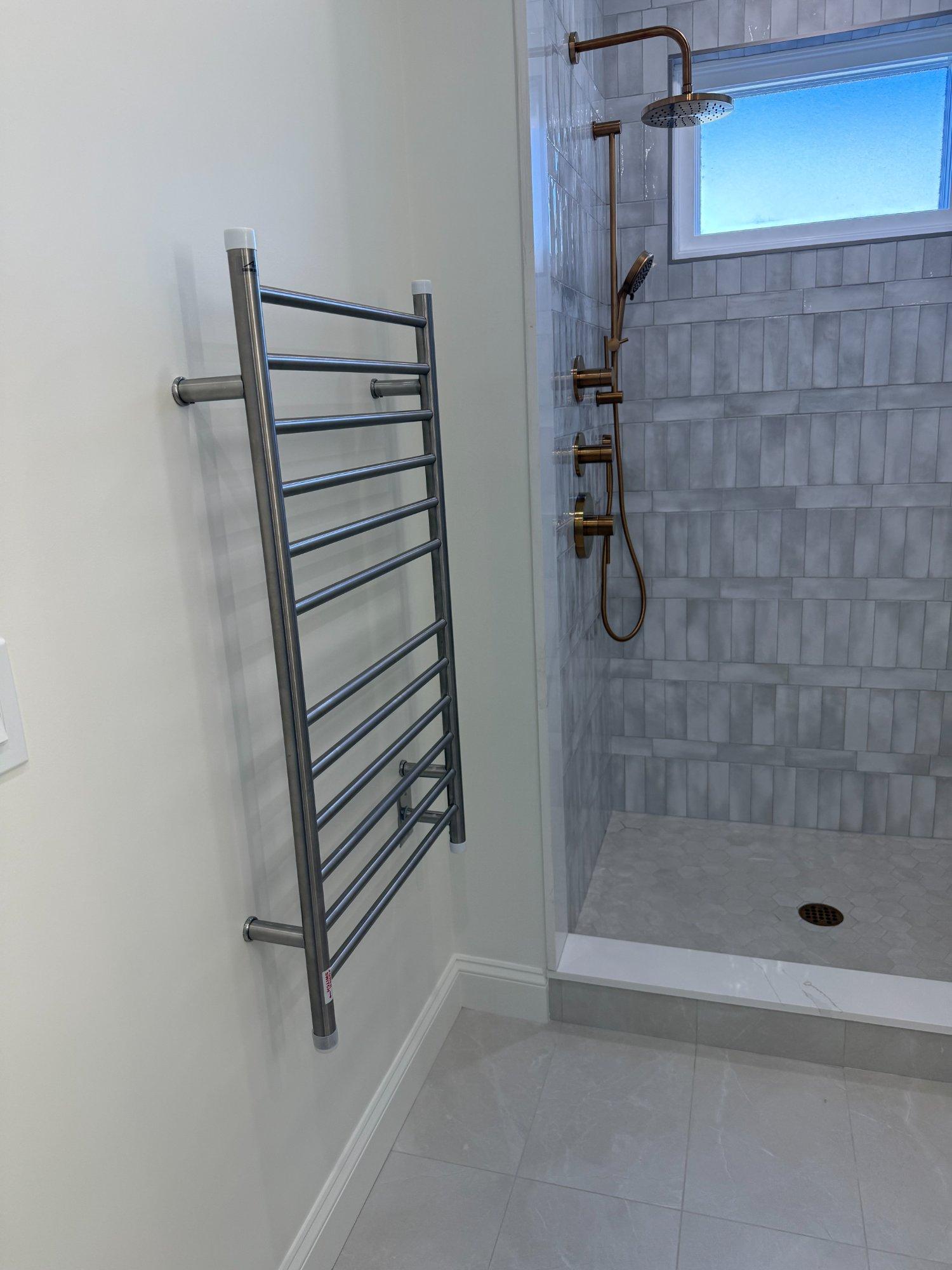 Heated towel warmer beside tiled walk-in shower in master bathroom