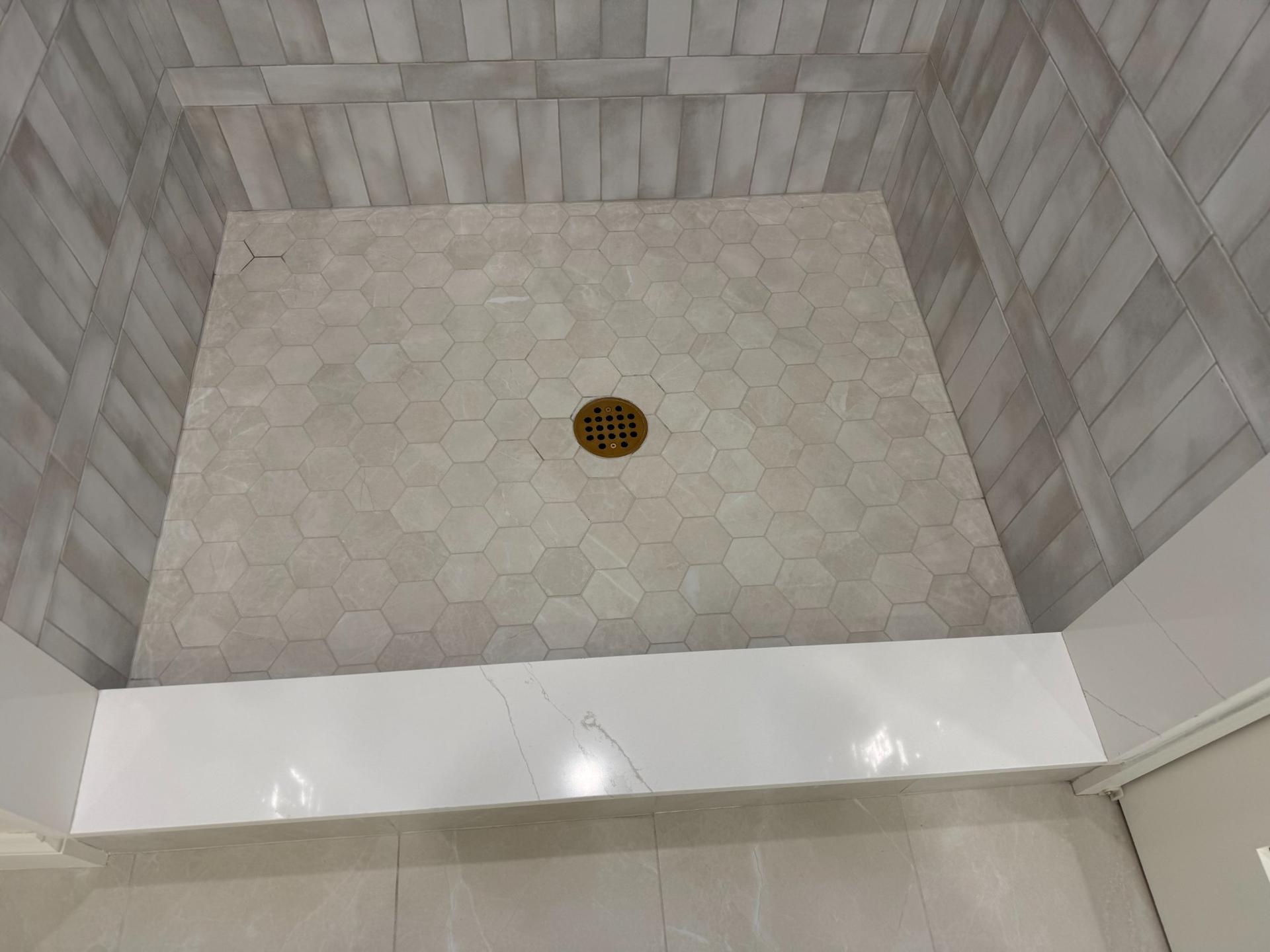 Shower floor with hexagon marble mosaic tile and brushed gold center drain
