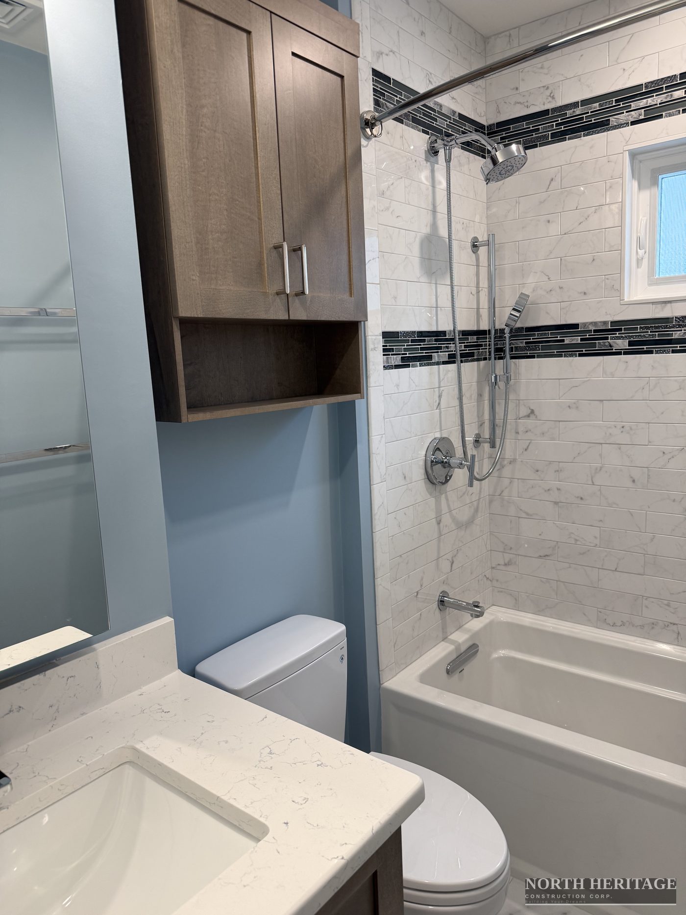 Bathroom vanity with quartz countertop and marble tile tub surround